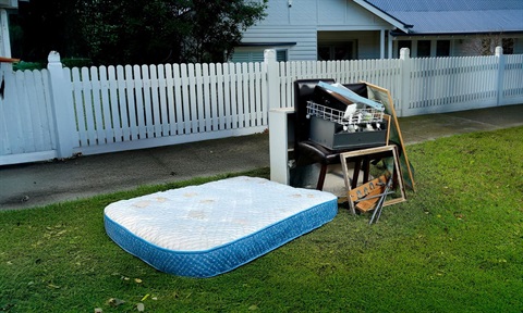 A single mattress out for collection, and a single collection of hard waste- side-by-side, the mattress laying down next to the hard waste that is neatly stacked on a nature strip within the 1 cubic metre threshold
